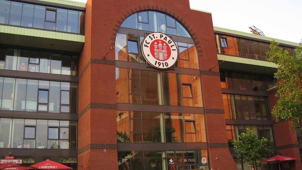 อาคารอิฐสีแดงพร้อมตราสัญลักษณ์วงกลม FC ST. PAULI 1910 ขนาดใหญ่ติดบนซุ้มประตูทางเข้า